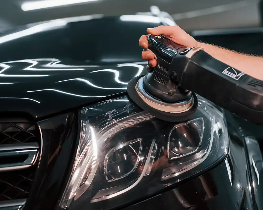Mecánico realizando el pulido de faros de un coche.